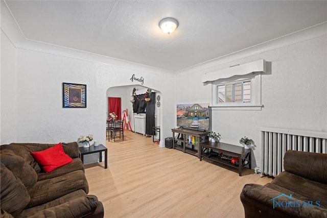 living room featuring crown molding, hardwood / wood-style flooring, and radiator heating unit