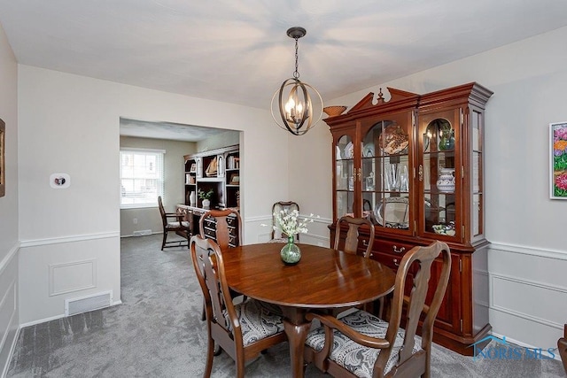 carpeted dining room with an inviting chandelier