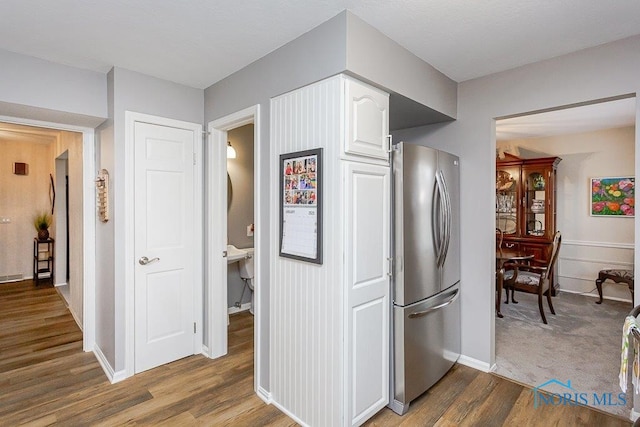 kitchen featuring dark wood-type flooring, stainless steel refrigerator, and white cabinets