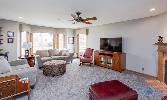 carpeted living room with a brick fireplace and ceiling fan