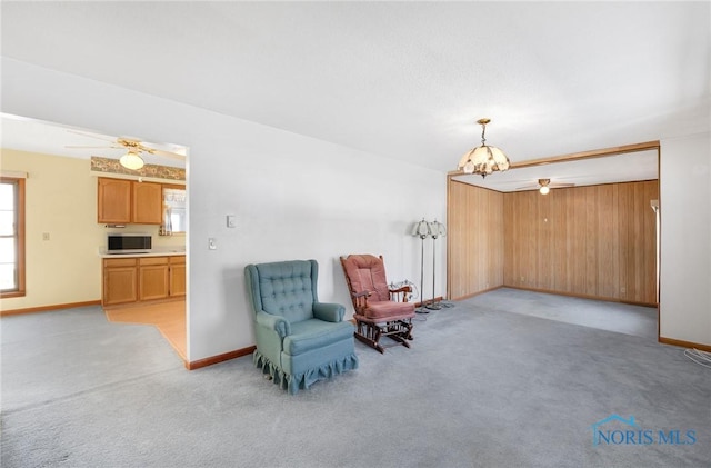 sitting room with ceiling fan with notable chandelier and light colored carpet