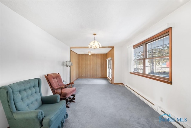 sitting room featuring light colored carpet, wood walls, a chandelier, and baseboard heating