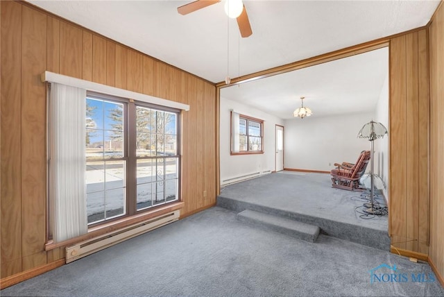 carpeted empty room with ceiling fan with notable chandelier, baseboard heating, and wood walls