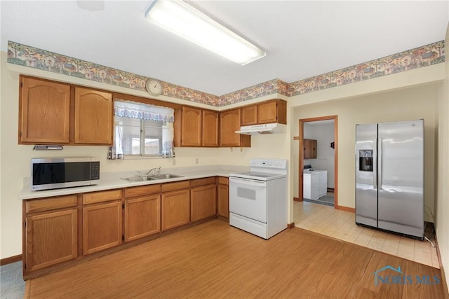 kitchen featuring sink, light hardwood / wood-style flooring, washer / clothes dryer, and appliances with stainless steel finishes