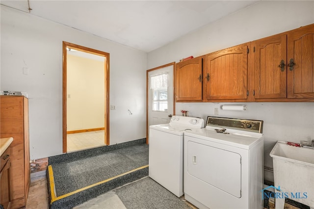 clothes washing area with washer and dryer, sink, and cabinets