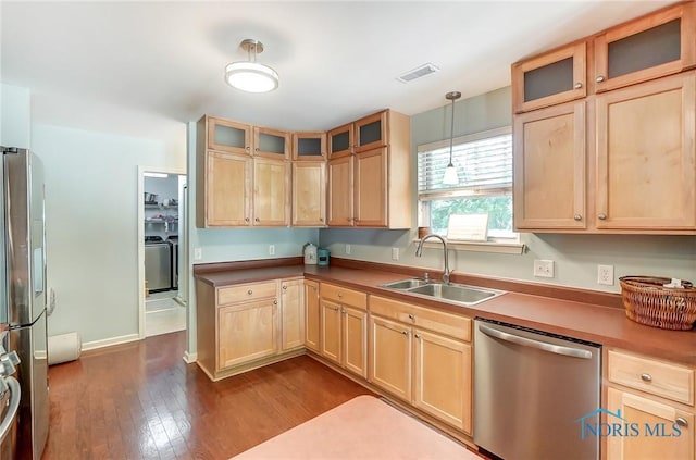 kitchen featuring sink, hanging light fixtures, appliances with stainless steel finishes, dark hardwood / wood-style floors, and washer / clothes dryer