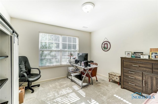 home office featuring light carpet, plenty of natural light, and a barn door