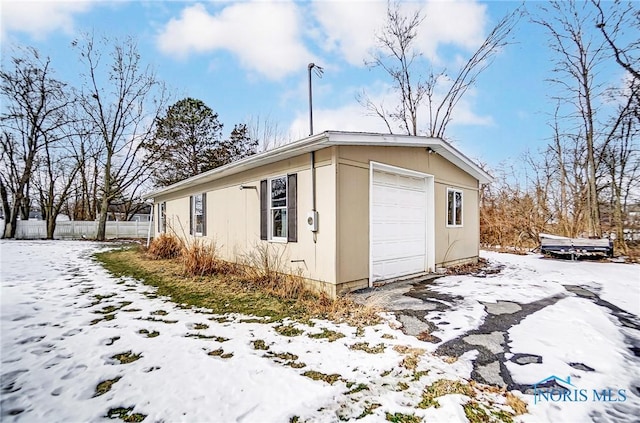 view of snow covered exterior featuring a garage and an outdoor structure