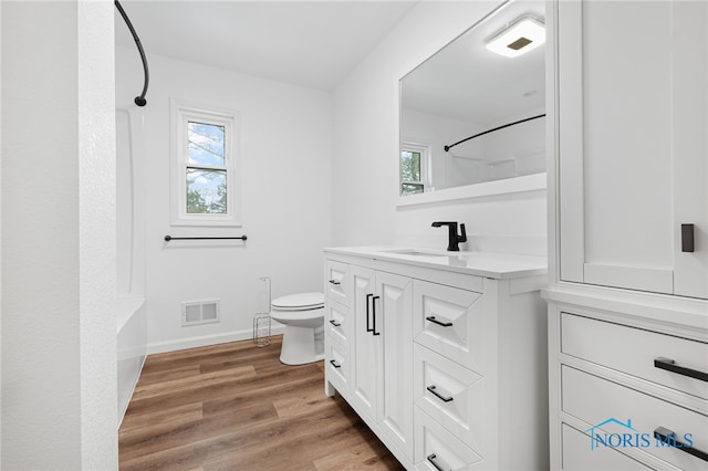 full bathroom featuring vanity, hardwood / wood-style flooring, toilet, and washtub / shower combination