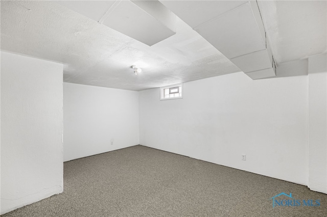 basement featuring carpet and a textured ceiling