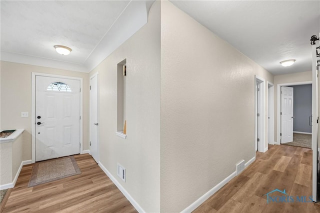 foyer entrance with a barn door and light hardwood / wood-style flooring