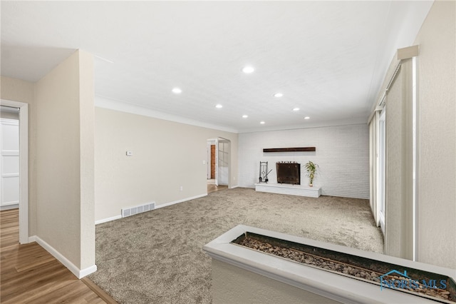 unfurnished living room featuring crown molding, a brick fireplace, and light carpet