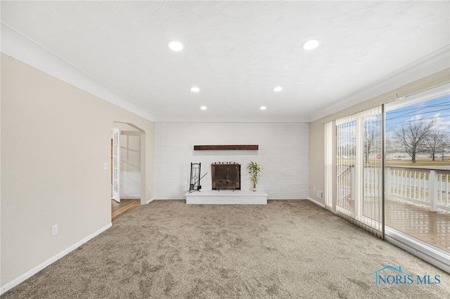 unfurnished living room featuring crown molding, carpet, and a fireplace