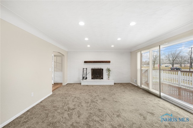 unfurnished living room with crown molding, carpet flooring, and a brick fireplace