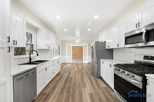 kitchen with sink, ceiling fan, appliances with stainless steel finishes, white cabinetry, and dark hardwood / wood-style floors