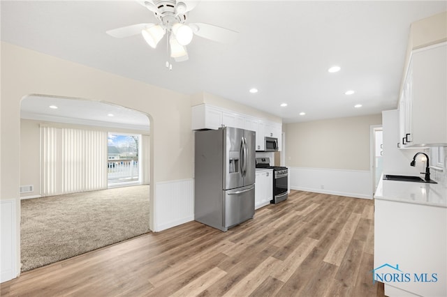 kitchen featuring sink, white cabinets, ceiling fan, stainless steel appliances, and light wood-type flooring