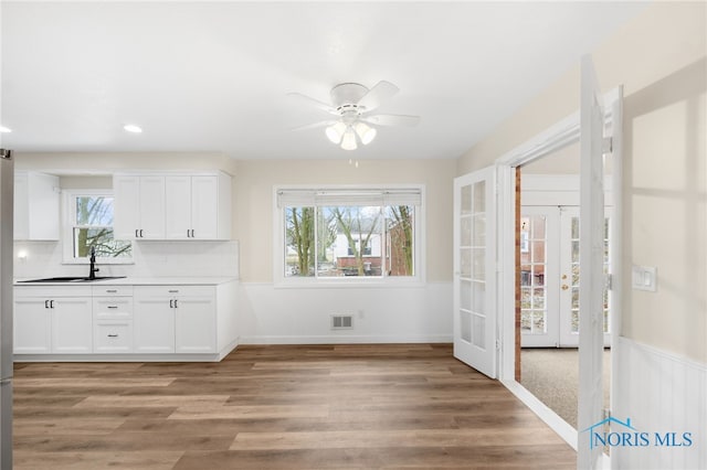 unfurnished dining area featuring hardwood / wood-style flooring, sink, ceiling fan, and french doors