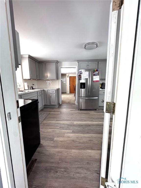 kitchen with gray cabinetry, backsplash, dark hardwood / wood-style flooring, and stainless steel refrigerator with ice dispenser