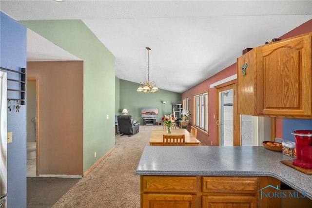 kitchen with lofted ceiling, hanging light fixtures, dark colored carpet, and an inviting chandelier