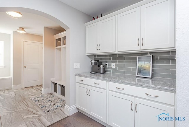 kitchen with white cabinetry, decorative backsplash, and light stone countertops