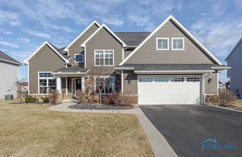 view of front of property featuring cooling unit, a garage, and a front lawn