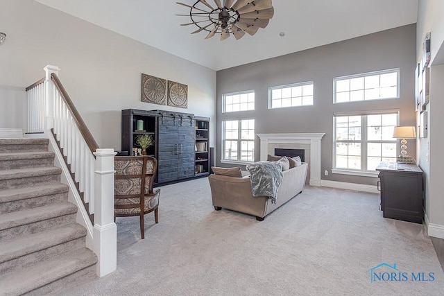 living room with light carpet, a towering ceiling, and ceiling fan