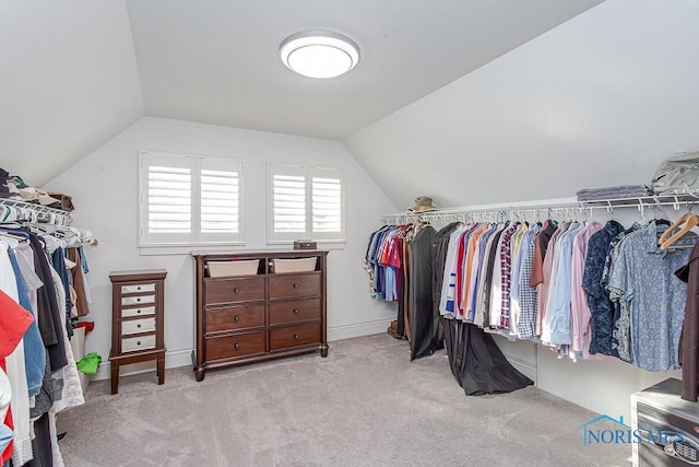 walk in closet with vaulted ceiling and light colored carpet