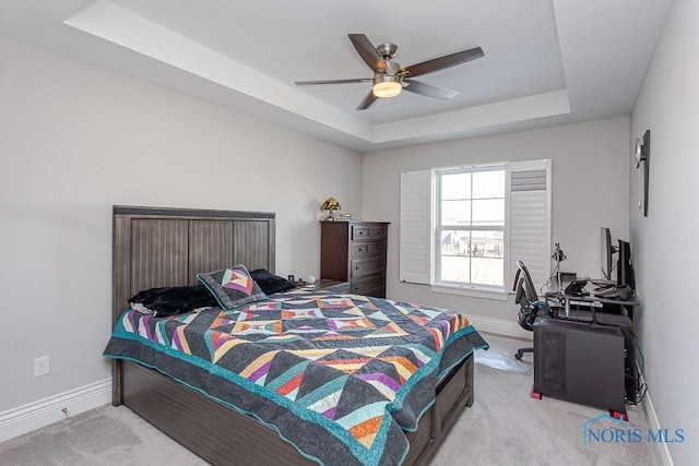 bedroom featuring light colored carpet, ceiling fan, and a tray ceiling