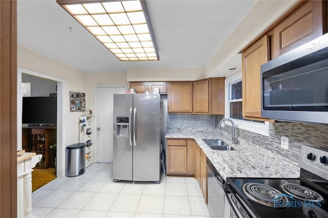 kitchen featuring light stone countertops, appliances with stainless steel finishes, sink, and backsplash