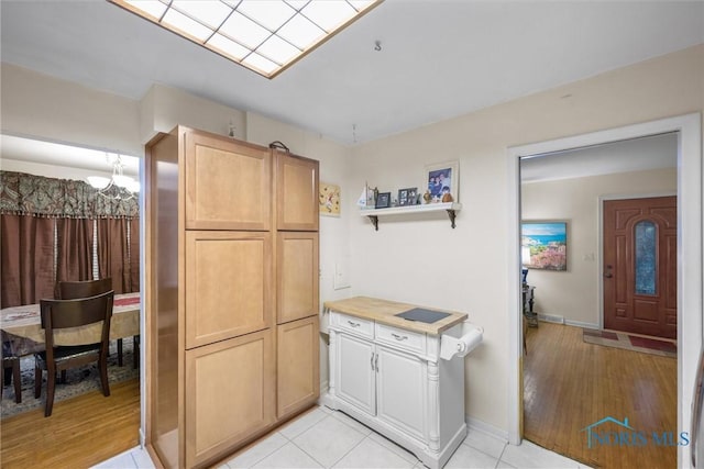 kitchen featuring light wood-type flooring, a chandelier, and light brown cabinets