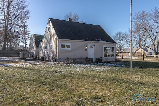 rear view of property with cooling unit and a yard