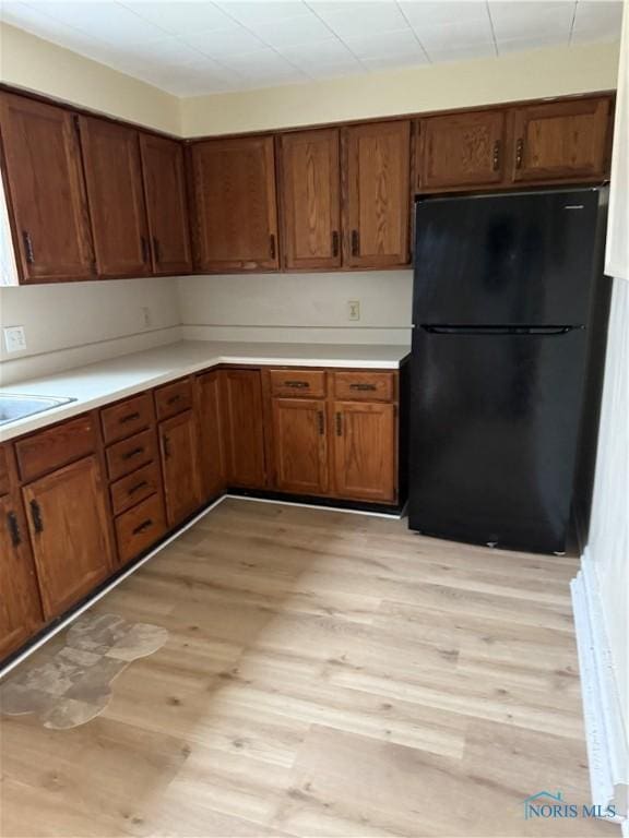 kitchen with black fridge, sink, and light wood-type flooring