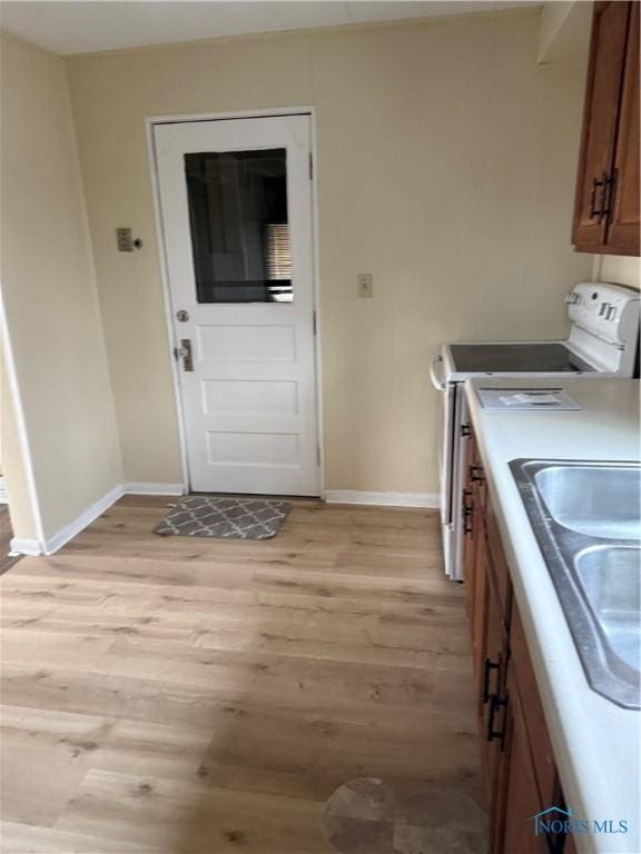 kitchen with white electric range oven, sink, and light wood-type flooring