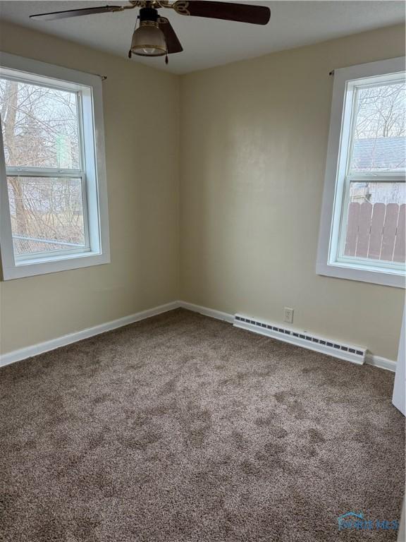 carpeted spare room with ceiling fan and a baseboard radiator