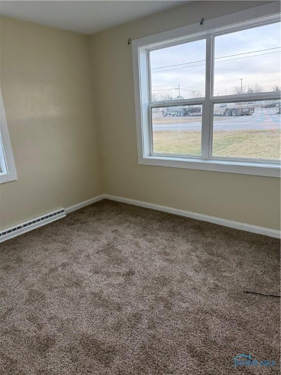 empty room with a baseboard radiator and carpet