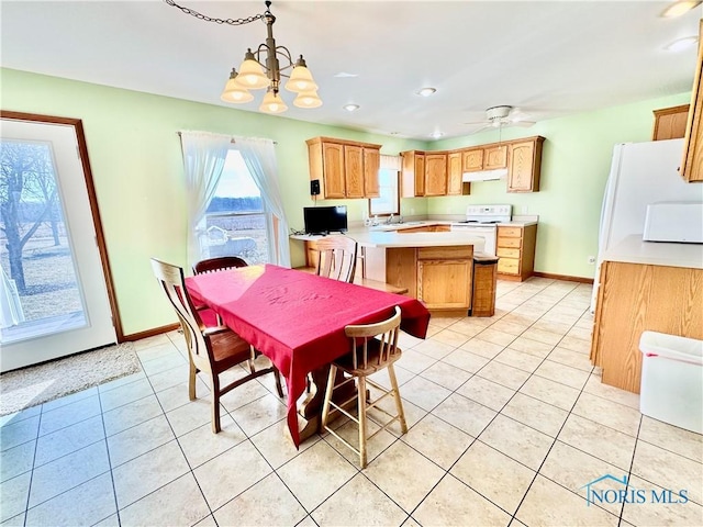 dining area with light tile patterned flooring, ceiling fan with notable chandelier, and sink