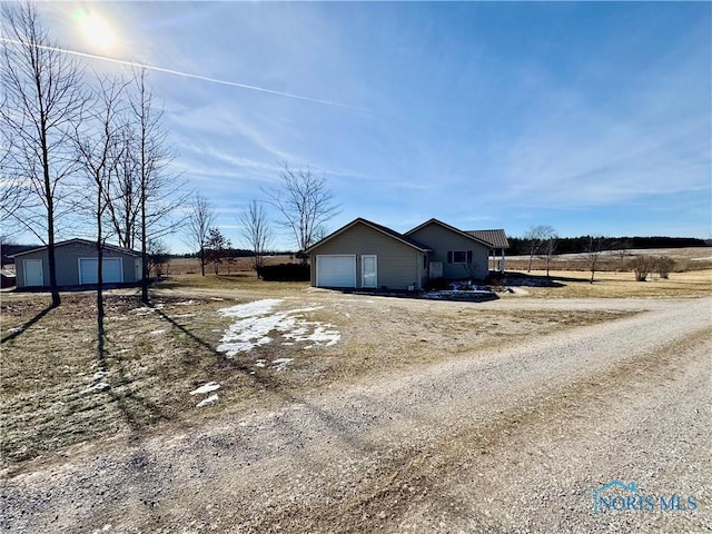 view of property exterior with a garage, an outdoor structure, and a rural view