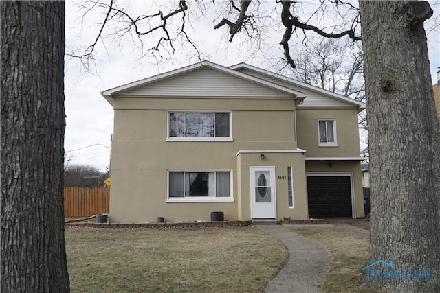 view of property featuring a garage and a front lawn