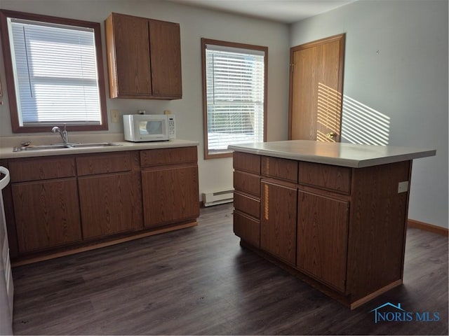 kitchen featuring sink, dark wood-type flooring, a kitchen island, and a baseboard heating unit