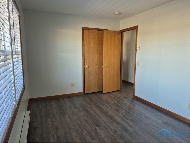 unfurnished bedroom with a baseboard radiator and dark wood-type flooring