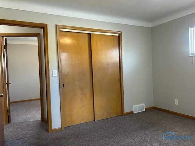 unfurnished bedroom featuring a closet and dark colored carpet