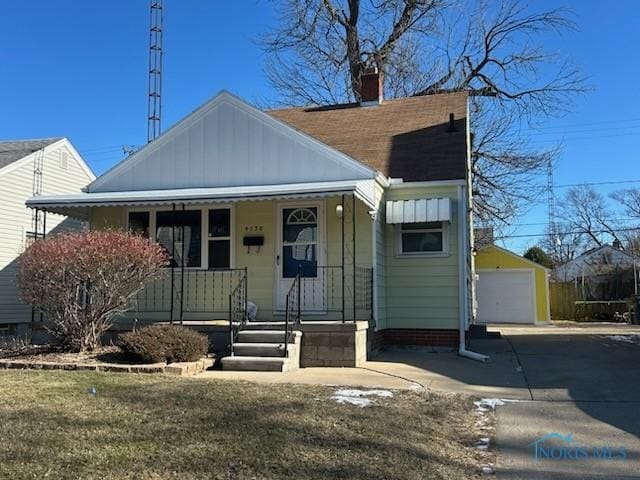 bungalow-style home with an outbuilding, a garage, a front yard, and a porch