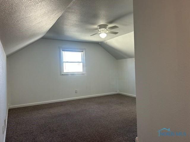 additional living space with ceiling fan, lofted ceiling, a textured ceiling, and dark colored carpet