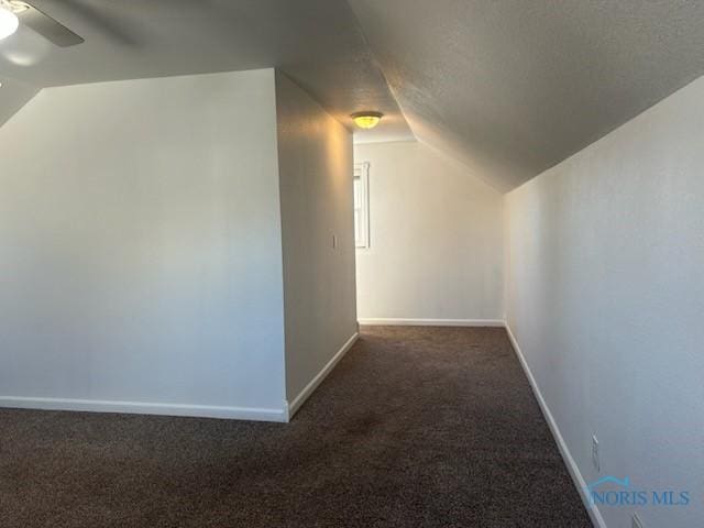 additional living space featuring dark carpet, ceiling fan, and vaulted ceiling