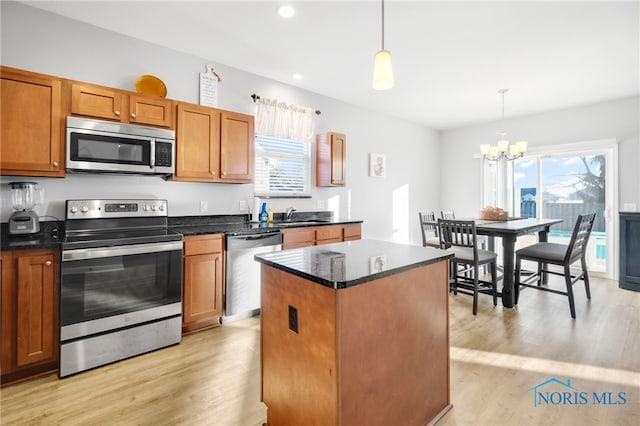 kitchen featuring stainless steel appliances, a center island, hanging light fixtures, and light hardwood / wood-style flooring