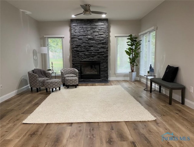 living area with hardwood / wood-style floors, a fireplace, and ceiling fan