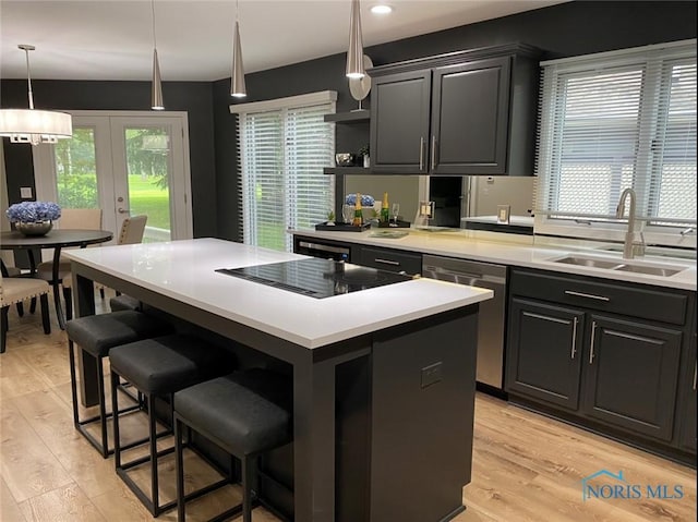 kitchen featuring dishwasher, sink, a kitchen bar, a center island, and black electric cooktop