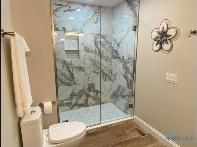 bathroom with a shower with door, hardwood / wood-style floors, and toilet