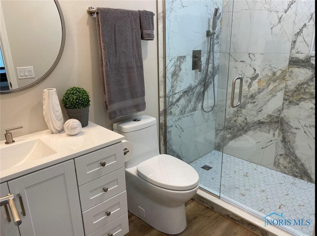 bathroom with a shower with door, wood-type flooring, vanity, and toilet