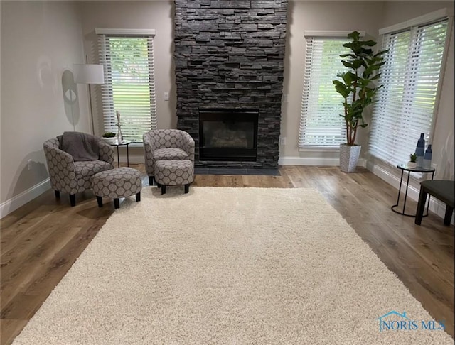 living area featuring hardwood / wood-style flooring, a stone fireplace, and a wealth of natural light